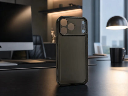 Røget sort transparent iPhone-cover stående på mørkt skrivebord i stilfuldt kontor med dæmpet belysning